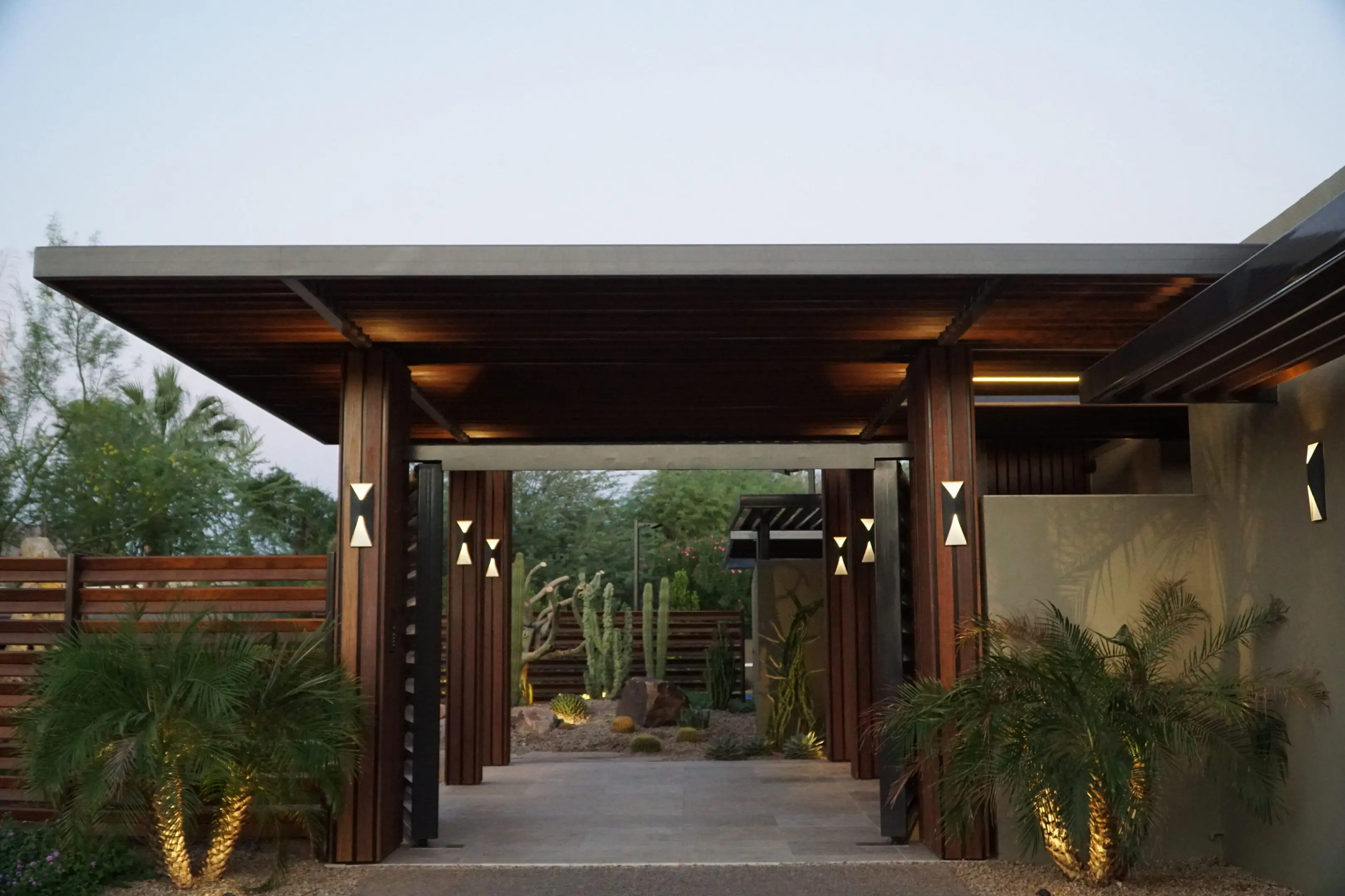 Elegant outdoor entrance with wooden pillars and lush greenery.