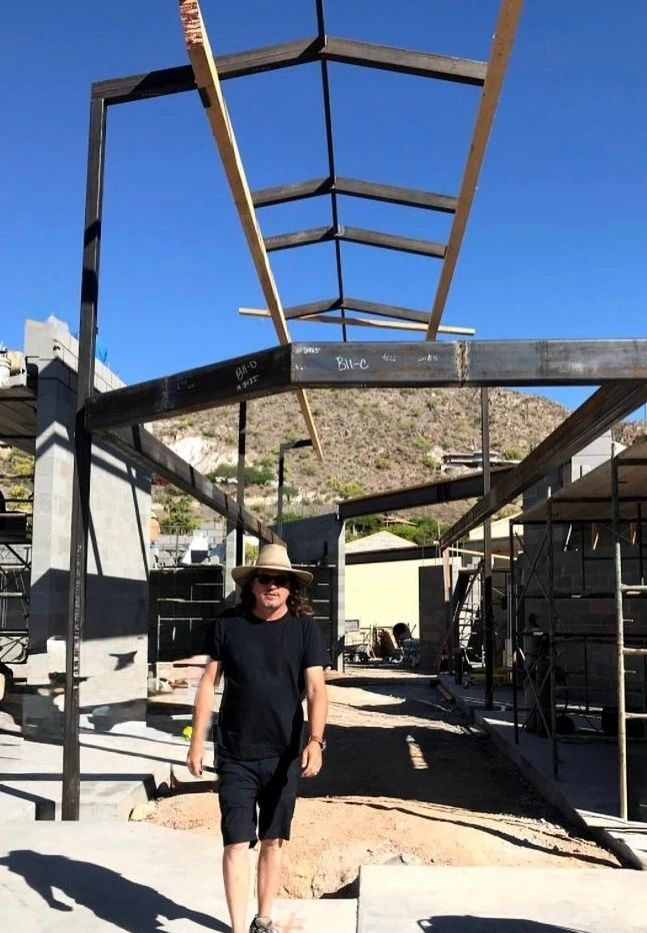 Man standing under a metal framework in a construction site.