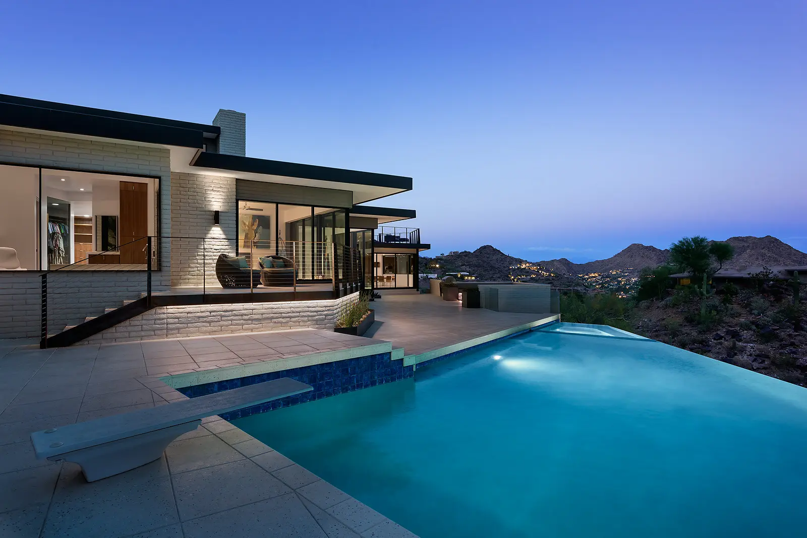 Modern house with a pool overlooking a scenic mountain view at dusk.