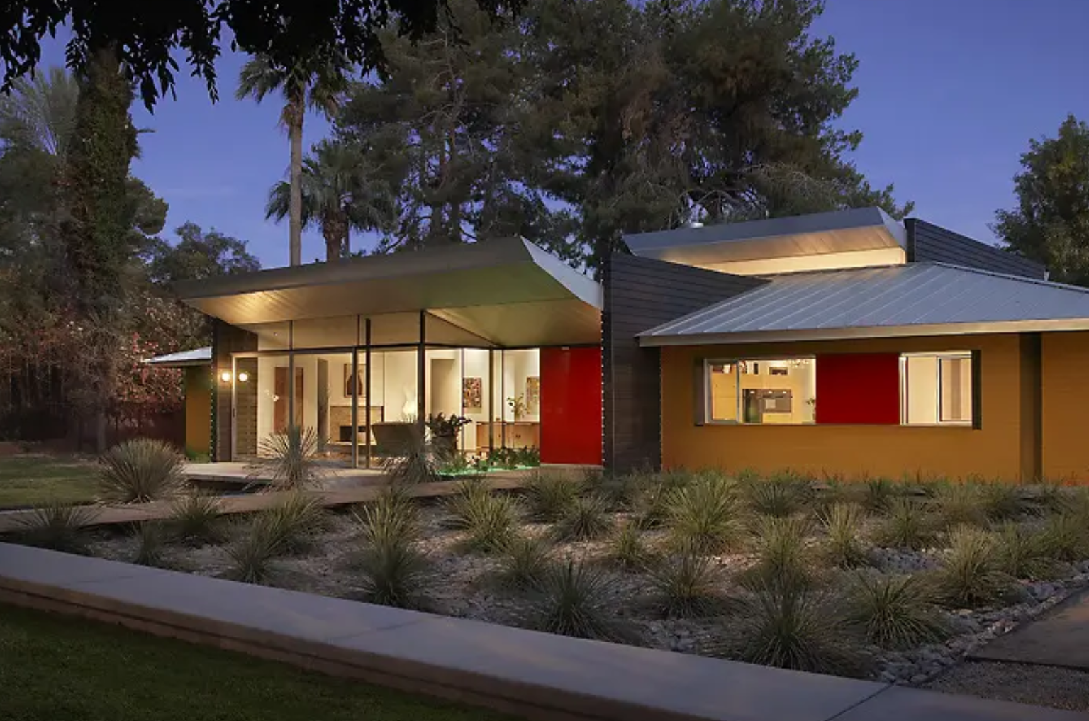 Modern house with warm lighting under a twilight sky.